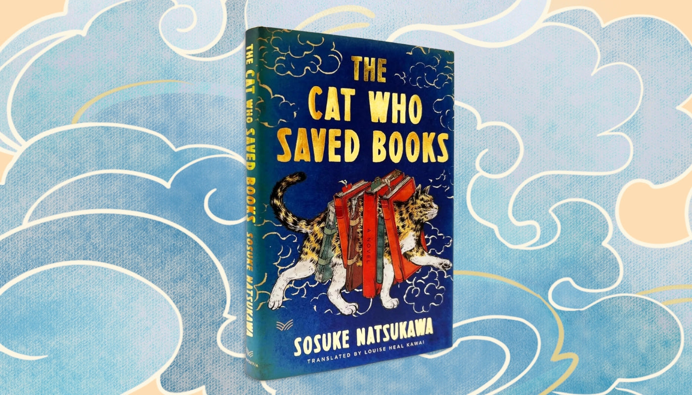 The book 'The Cat Who Saved Books' by Sosuke Natsukawa, standing upright against a decorative blue and cream cloud-patterned background. The cover features a dark blue background with yellow title text and an illustration of a leopard carrying red books.